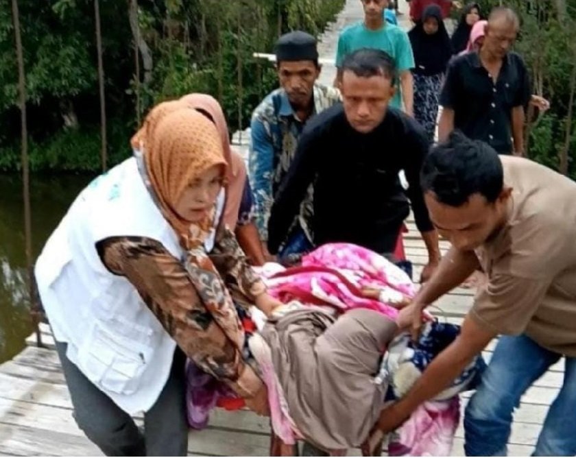Warga bersama bidan desa mengevakuasi Intan Sinarwati, ibu hamil asal Kampung Payung, Kecamatan Linge, Aceh Tengah, menggunakan gerobak sorong melewati jembatan gantung yang tidak dapat dilalui kendaraan roda empat, Rabu (27/8/2025). (Foto: Dok. Warga)